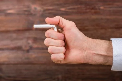 Man breaks a cigarette in his hand. Fight against smoking concept. Stock Photos