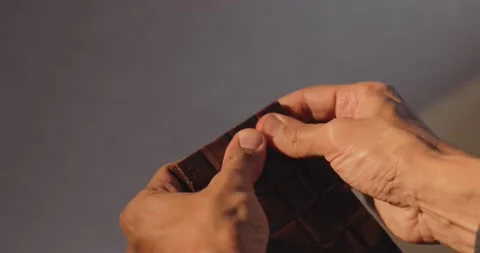 Man breaks dark chocolate bar Stock Footage 142956439