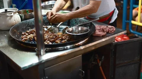 Man breaks eggs on large pan at hawker food stall Stock Footage 62902355