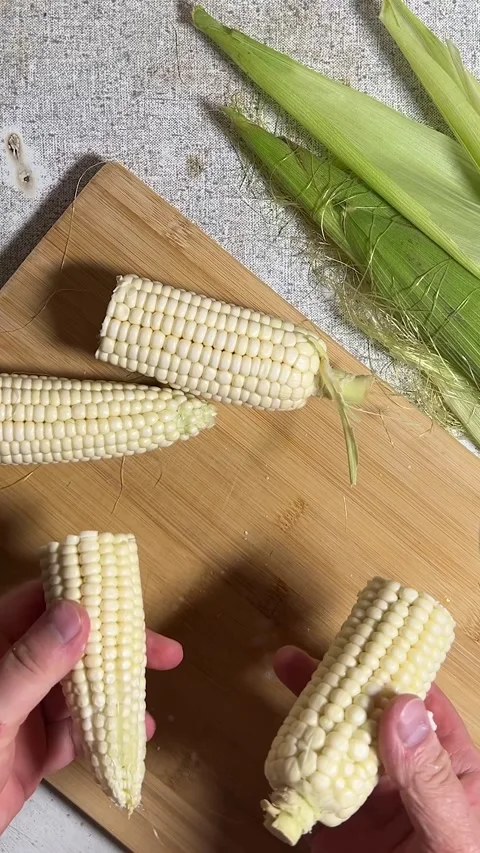 Man breaks fresh, raw ear of white corn in half. Cooking process Video stock 278684986