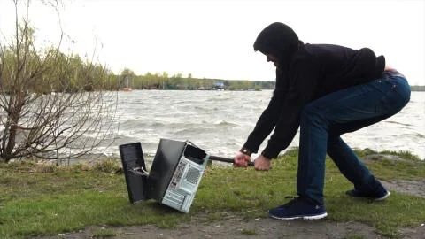 Man breaks a hammer system unit computer. Man with a sledge hammer and destroys 스톡 사진