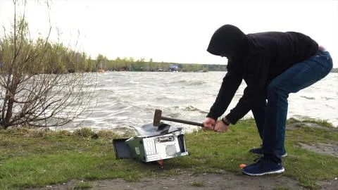 Man breaks a hammer system unit computer. Man with a sledge hammer and destroys 스톡 사진