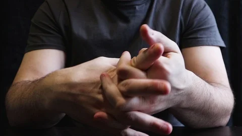 A man breaks his knuckles and fingers. Cracking knuckles on the table. Stock Footage 123537028