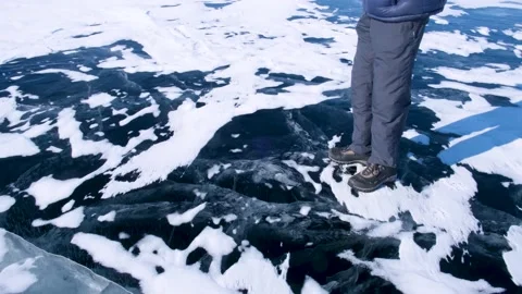 A man breaks a small ice floe on the icy surface of a lake in winter. Stock Footage 152122837