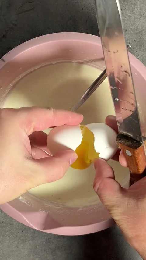 Man breaks white chicken eggs with knife on pink bowl Stock Footage 329666817