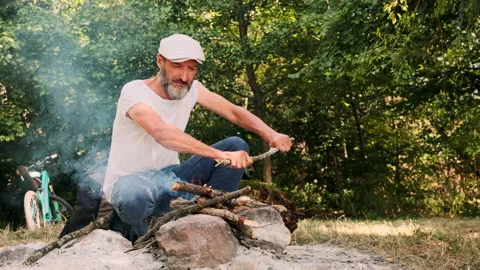 The man breaks wood and throws it into the fire. Stock Footage 148337557