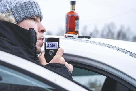 A man with a breathalyzer in the car Stock Photos