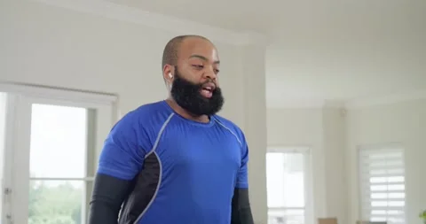 Man breathing, lifting hexweight with earbuds in blue shirt curling for biceps Stock Footage 342803111