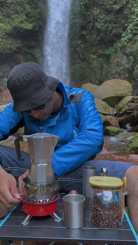 Man Brewing Coffee with Moka Pot by Waterfall in Nature, Vertical Shot Stock Footage 321104464