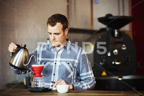 A Man Brewing Coffee Using A Filter Paper, And Drinking It.