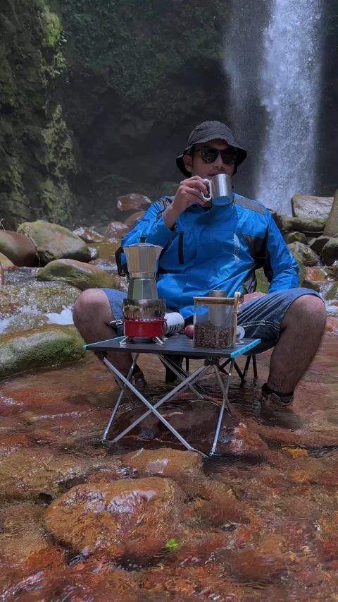 Man Brewing Coffee by Waterfall River Camp Relaxation Vertical Stock Footage 321104313