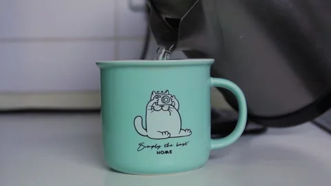 Man brews black tea in a cup. Pouring water from a teapot into a green mug Stock Footage 201846881