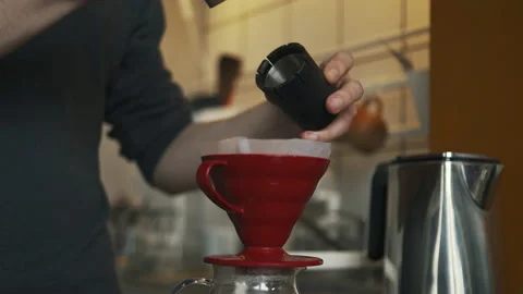 A man brews ground coffee through a paper filter in the kitchen in the morning Stock Footage 171154978