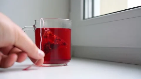 Man brews raspberry tea using pyramid tea bag in glass cup Stock Footage 117961680