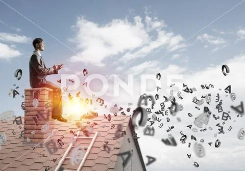 Man on brick roof working with smartphone and symbols flying around Stock Photos