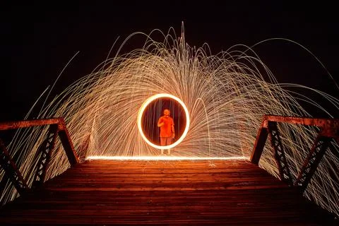Man on a bridge with a circle of light and sparks at night 库存照片