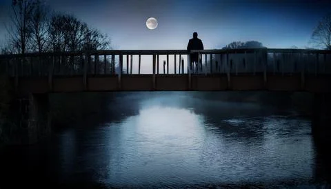 Man on a bridge under moonlight Stock Photos