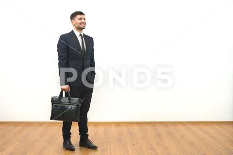 The man with a briefcase standing on the white wall background Stock Photos
