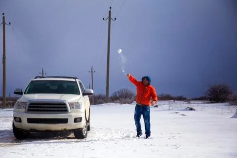 A man in bright winter clothes throws a snowball. Stock Photos