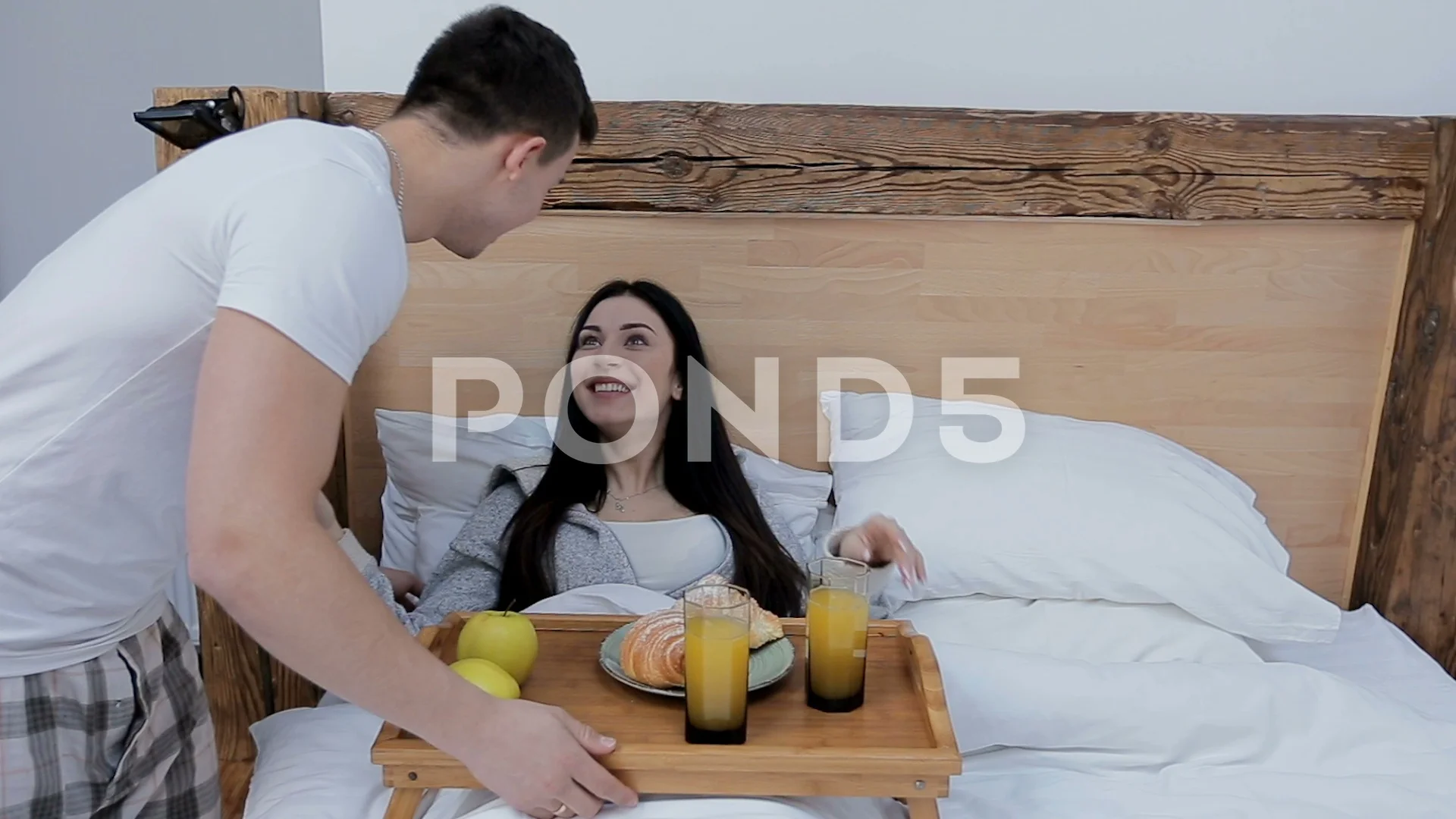Man bringing wife breakfast in bed on tray carry and surprising happy woman