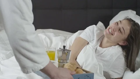 Man brings breakfast in bed to his girlfriend who is sleeping Stock Footage 73349116