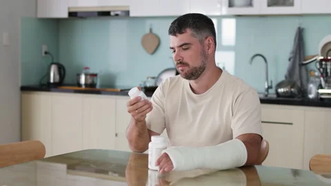 Man with broken arm reading medication bottle. Stock Footage 289541009