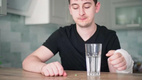 A man with a broken hand drinks painkillers. Temporary health problems. Hand in Stock Footage 132998886