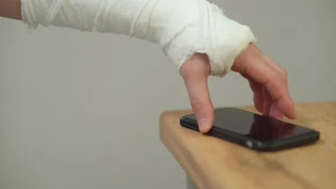 A man with a broken hand in a plaster casts takes a smartphone Stock Footage 234134786