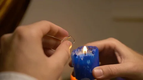 The man brought white, transparent stone to flame of blue candle and examined it Stock Footage 105861008