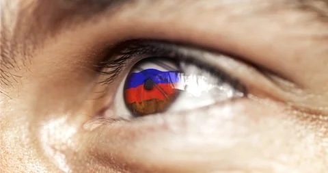 Man brown eye in close up with the flag of russia in iris with wind motion. vide Stock Footage 120817042