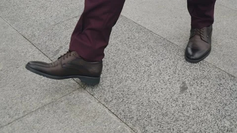 A man in brown shoes is walking down a city street Stock Footage 163893596