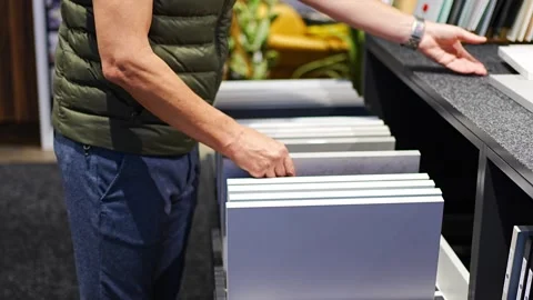 Man browses cabinet door samples in furniture showroom. Choosing colors and Stock Footage 346298116