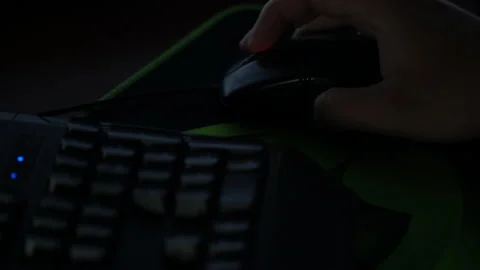 A man browses a website with a mouse in front of a computer in a dark room Stock Footage 237374397