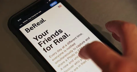 Man browsing BeReal website page on an iPhone Stock Footage 220405561