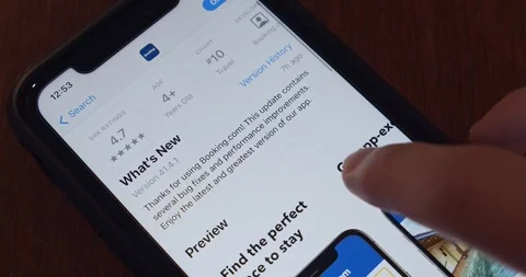 Man browsing Booking.com app in App Store seen in an iPhone Vidéo 253339539