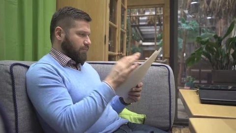 Man browsing documents, files, looking, smiling at camera, in cafe, steadicam 库存影片 73076128