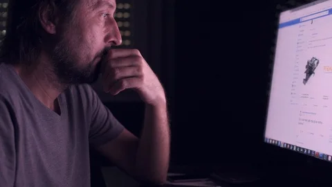 Man is browsing Facebook news feed page on home computer Stock Footage 89353196