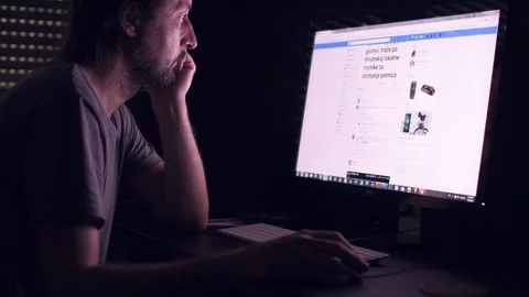 Man is browsing Facebook news feed page on home computer Stock Footage 90377450