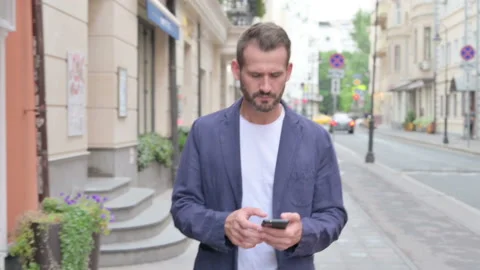 Man Browsing Internet on Smartphone while Walking Down the Street, Slow Motion Stock Footage 158362669