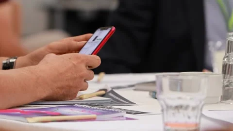 Man browsing an online catalog on red smartphone during event conference Stock-Footage 254660926
