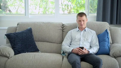 Man browsing phone on couch at home. Happy mood. Stock Footage 105320047