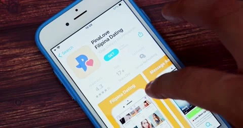 Man browsing PinaLove introduction page on App Store on iPhone on wooden table Stock Footage 207548743