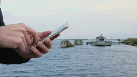 Man browsing on a smartphone and a sauna floats in the ocean Stock Footage 81258643