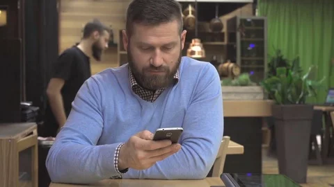 Man browsing smartphone, looking at camera, in pub, cafe, indoor, steadicam Vidéo 73067646