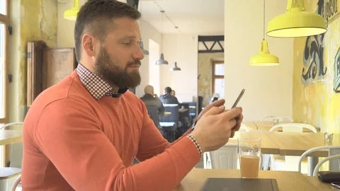 Man browsing smartphone, looking at camera, profile shot, in cafe, steadicam Vídeo Stock 73266479