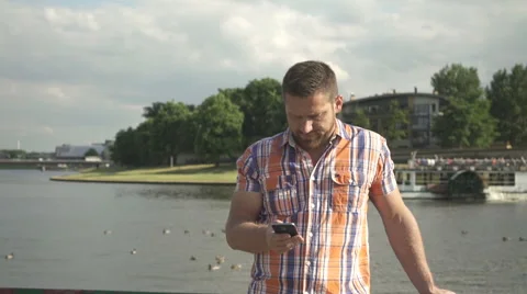 Man browsing smartphone by the river. Vídeo Stock 52698702