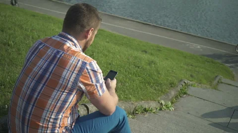 Man browsing smartphone, sitting on stairs by the river Vídeo Stock 52718285