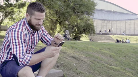 Man browsing smartphone, sitting on stairs. Slider shot, left. Video stock 67246292