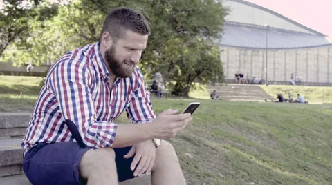 Man browsing smartphone, sitting on stairs. Slider and pan shot right. 库存影片 67246827