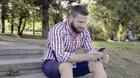 Man browsing smartphone, sitting on stairs. Slider and pan shot. 動画素材 67247153